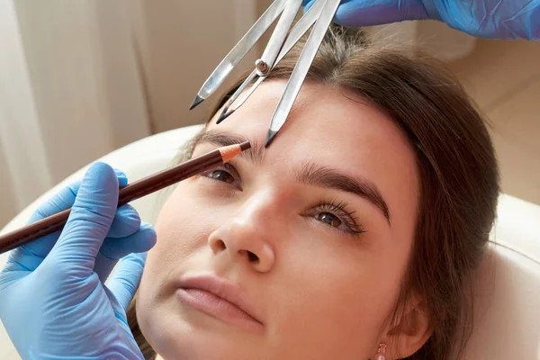 Cosmetologist measures the proportions of the eyebrows with the ruler.