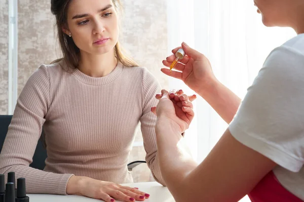 Cuidado de las cutículas. Mano femenina aplicando aceite sobre las uñas — Foto de Stock