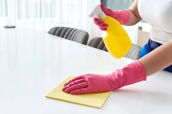 집에서 식탁을 닦을 때는 수건과 장갑을 사용하여 살균제 분말 병을 문질러 식탁 표면을 소독 한다. COVID-19 예방 주사 내부. — 스톡 사진