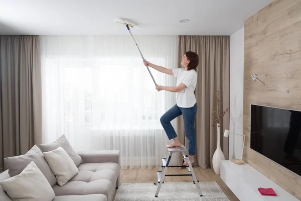 Mujer limpiando el techo con una fregona. Ama de casa limpieza sala de estar — Foto de Stock