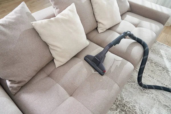 Staubsauger auf einem Sofa im leeren Wohnzimmer einer modernen Wohnung — Stockfoto