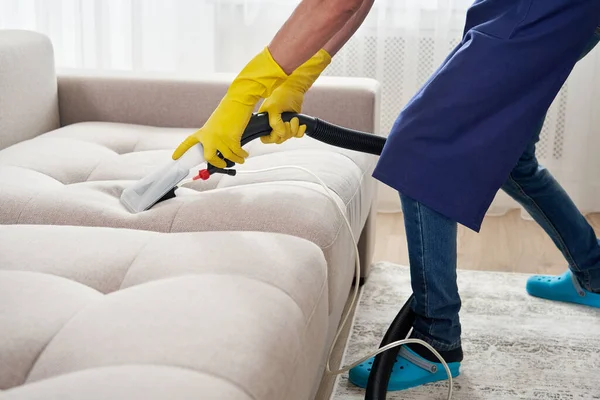 Close-up of housekeeper holding modern washing vacuum cleaner and cleaning dirty sofa with professionally detergent. Professional springclean at home concept — Stock Photo, Image