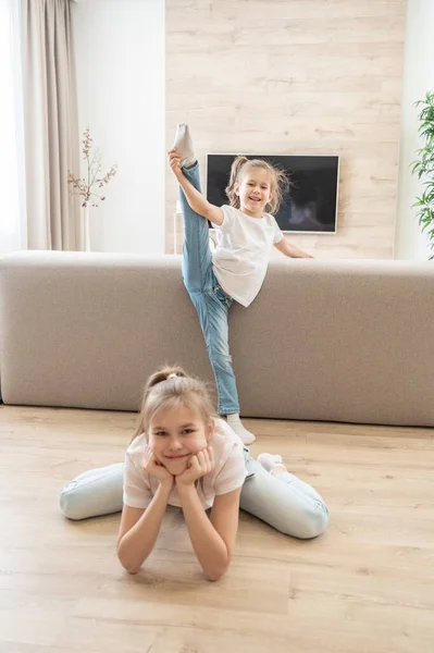 Zwei Mädchen machen Dehnübungen im heimischen Wohnzimmer. Freundliches Schwestern-Konzept — Stockfoto