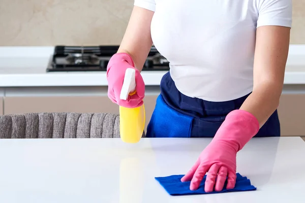 Vrouw schoonmaken home tafel ontsmetten keukentafel oppervlak met desinfecterende spray fles — Stockfoto