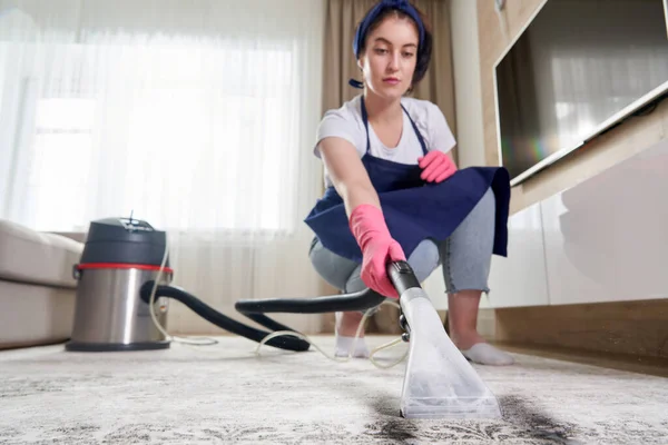 Žena úklid koberec v obývacím pokoji pomocí vysavače doma. Koncept úklidové služby — Stock fotografie