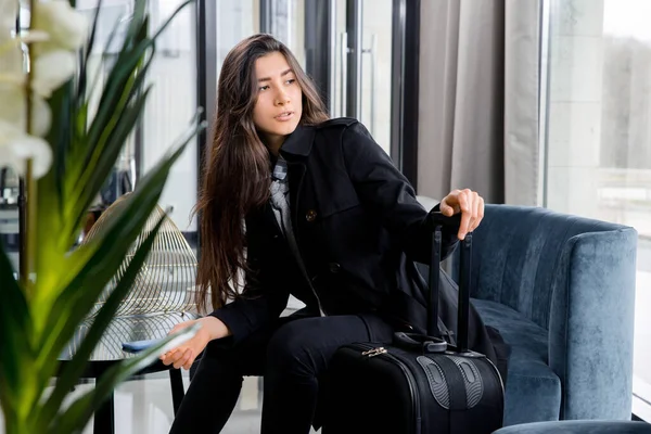 Frau sitzt mit Koffer in Hotellobby oder Flughafen-Lounge — Stockfoto