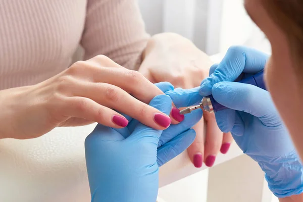 Manicure master uses an electric nail machine to remove nail polish hands in nail salon — Stock Photo, Image
