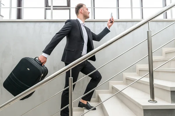 Podnikatel držící kufr běžící po schodech v moderní budově — Stock fotografie