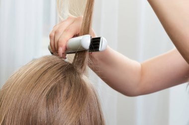 Saç stilisti kadın müşteri üzerinde çalışıyor.