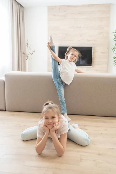 Zwei Mädchen machen Dehnübungen im heimischen Wohnzimmer. Freundliches Schwestern-Konzept — Stockfoto