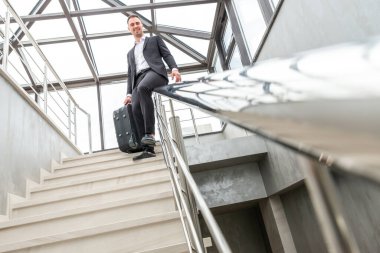 Modern iş binasında merdivenlerde kayan resmi takım elbiseli mutlu bir işadamı. Acele ve özgürlük kavramı