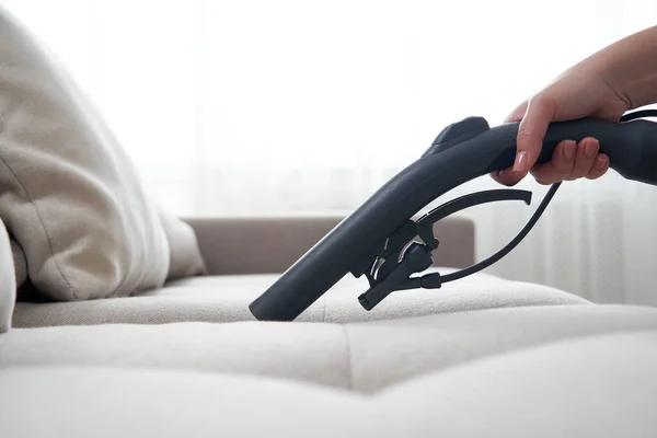 Young housewife Cleaning Sofa with Vacuum Cleaner in living room — Stock Photo, Image