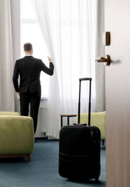 Otel odasında dikiz aynasından bakan koyu renk takım elbiseli işadamlarının...
