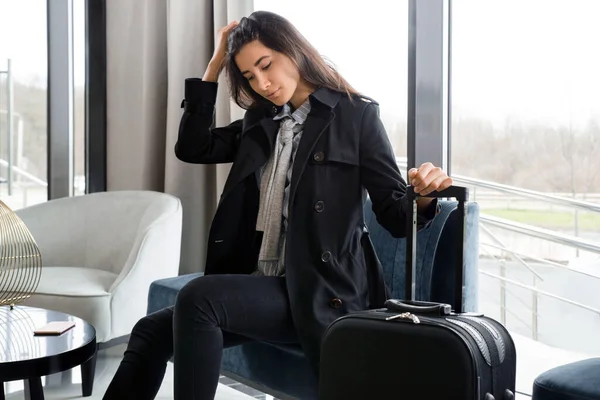 Žena sedící s kufrem v hotelové hale nebo v letištní hale — Stock fotografie