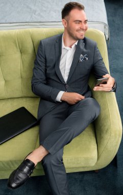 Neşeli iş adamı otel odasında bavuluyla iş gezisinde telefon kullanıyor.