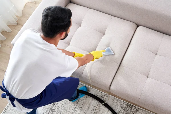 Großaufnahme der Haushälterin, die einen modernen Waschsauger in der Hand hält und das schmutzige Sofa mit professionellem Spülmittel reinigt. Professionelles Frühjahrsputz-Konzept — Stockfoto