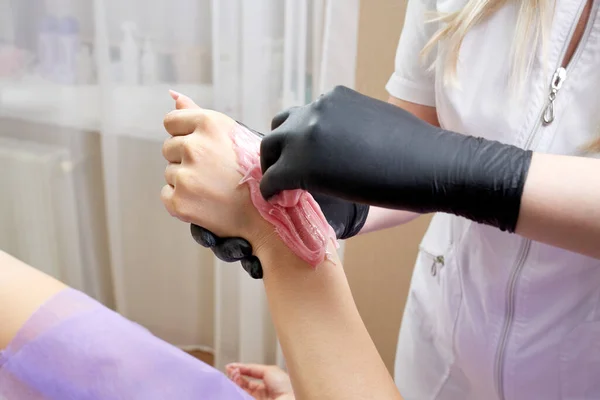 Waxing in beauty salon by professional. Beauty salon worker applying wax and tape to remove hair from arms — Stock Photo, Image