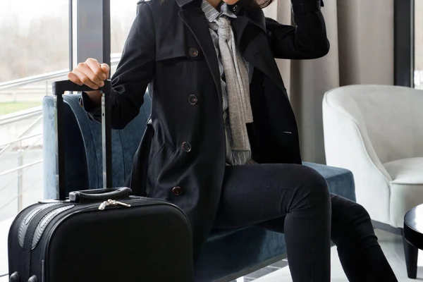 Bavullu bir kadın otel lobisinde ya da havaalanı salonunda oturuyor. — Stok fotoğraf
