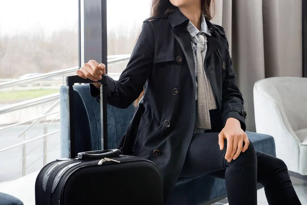Žena sedící s kufrem v hotelové hale nebo v letištní hale — Stock fotografie
