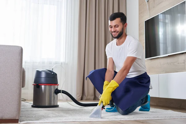Man Cleaning Carpet In The Living Room menggunakan Vacuum Cleaner Di Rumah. Konsep layanan pembersihan — Stok Foto