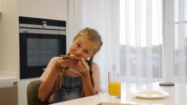 Genç kız mutfakta bir dilim pizza yiyor. Yavaş çekim