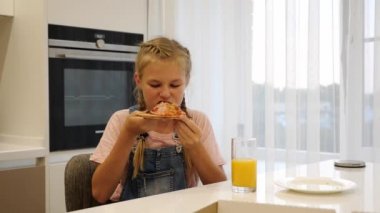 Genç kız mutfakta bir dilim pizza yiyor. Yavaş çekim