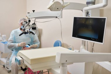 Diş mikroskobuyla çalışan dişçi ve modern dişçi kliniğinde hasta.