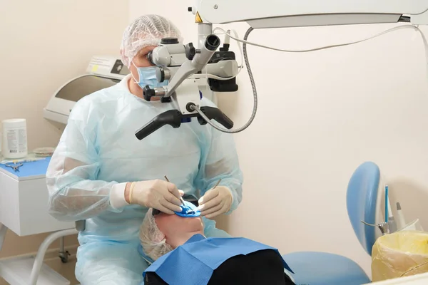 Dentist working with dental microscope and patient at modern dentist clinic — Stock Photo, Image