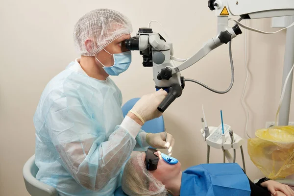 Tandarts werken met tandheelkundige microscoop en patiënt bij moderne tandarts kliniek — Stockfoto