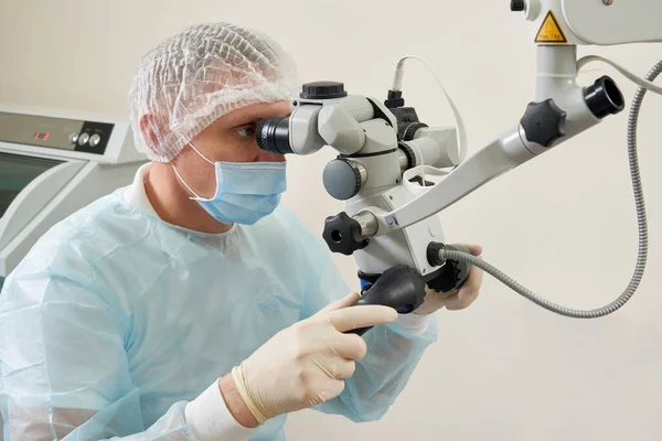 Стоматолог, работающий с зубным микроскопом и пациентом в современной стоматологической клинике — стоковое фото