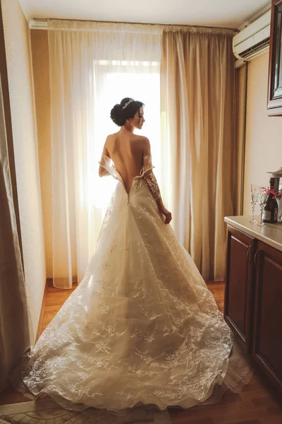 时尚图片 美丽的新娘 深色头发 穿着雅致的婚纱 头戴皇冠 早上在房间里摆姿势 — 图库照片