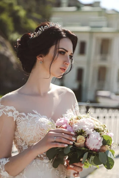 时尚的照片 美丽的新娘与深色的头发穿着优雅的婚纱摆在户外与招标花束 — 图库照片