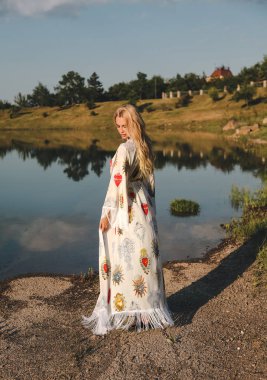 Açık sarı saçlı güzel seksi kadın fotoğrafı zarif yüzme elbiseli güzel doğa yerde, etrafı dağlarla çevrili bir göl poz moda