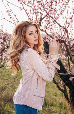 şık giysileriyle çiçeklenme şeftali bahçesinde poz sarışın saçlı güzel şehvetli kız moda açık fotoğraf