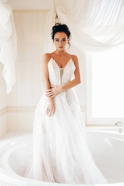 时尚内饰照片美丽的女人新娘与黑头发在豪华的婚纱礼服摆姿势在浴室 — 图库照片
