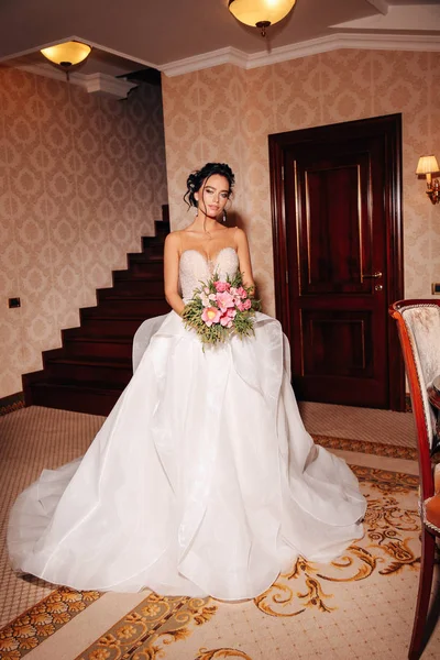 时尚照片美丽的新娘与长的黑发在豪华的婚纱礼服和配件摆在优雅的内饰 — 图库照片