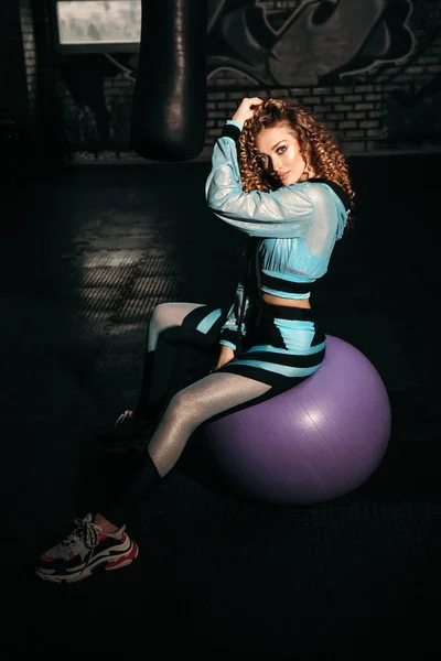 Mujer deportiva con el pelo rubio rizado en traje deportivo elegante tr —  Fotos de Stock
