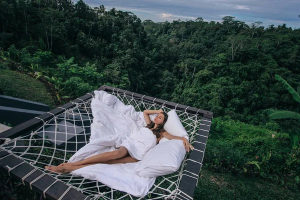 Schöne Frau mit dunklen Haaren entspannt sich im Open-Air-Bett mit ba — Stockfoto