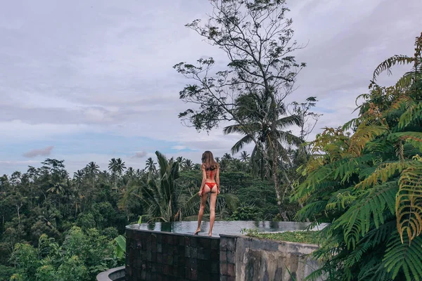 Schöne Frau mit dunklen Haaren im roten Bikini posiert am Rand — Stockfoto