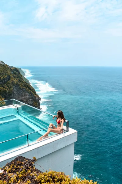 Woman with dark hair relaxing in transparent swimming pool with — Stock Photo, Image