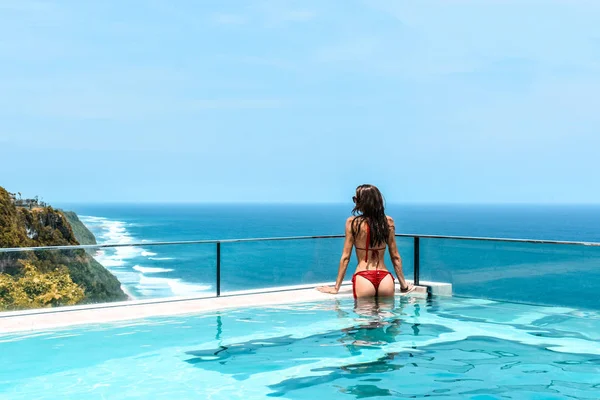 Woman with dark hair relaxing in transparent swimming pool with — Stock Photo, Image