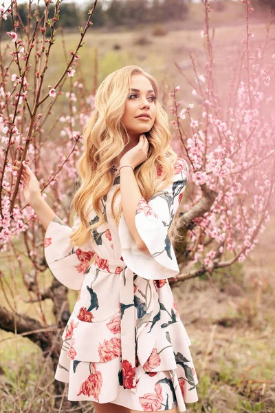 Menina bonita com cabelo loiro em vestido elegante posando entre fl — Fotografia de Stock