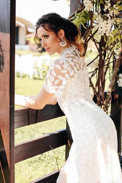 Piękna kobieta w eleganckiej białej sukni stwarzających w kwitnienia sterow — Zdjęcie stockowe