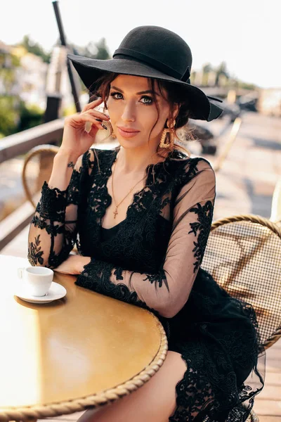Bela mulher sexy com cabelo escuro em vestido preto elegante e h — Fotografia de Stock