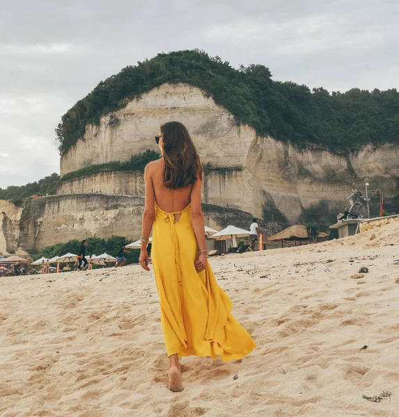 Beautiful woman with dark hair in elegant yellow dress walking o — Stock Photo, Image