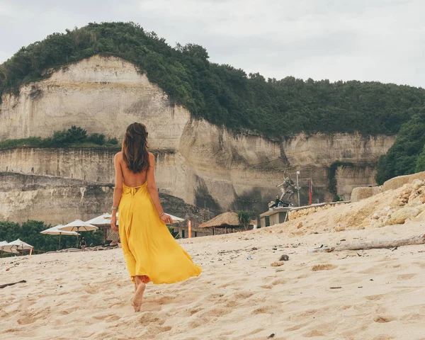 Beautiful woman with dark hair in elegant yellow dress walking o — Stock Photo, Image