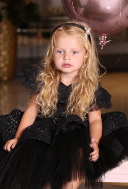 Sarışın, kıvırcık saçlı, zarif elbiseli güzel bir kız.