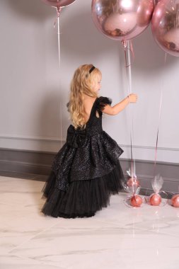 Sarışın, kıvırcık saçlı, zarif elbiseli güzel bir kız.