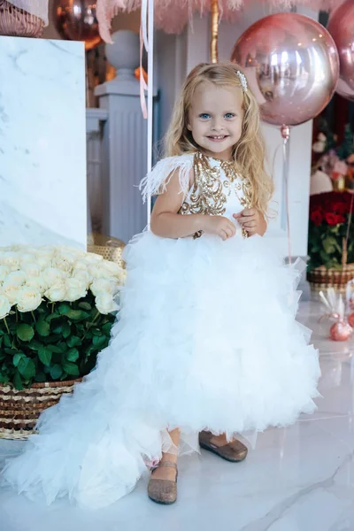 Sarışın, kıvırcık saçlı, zarif elbiseli güzel bir kız.