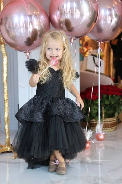 Sarışın, kıvırcık saçlı, zarif elbiseli güzel bir kız.